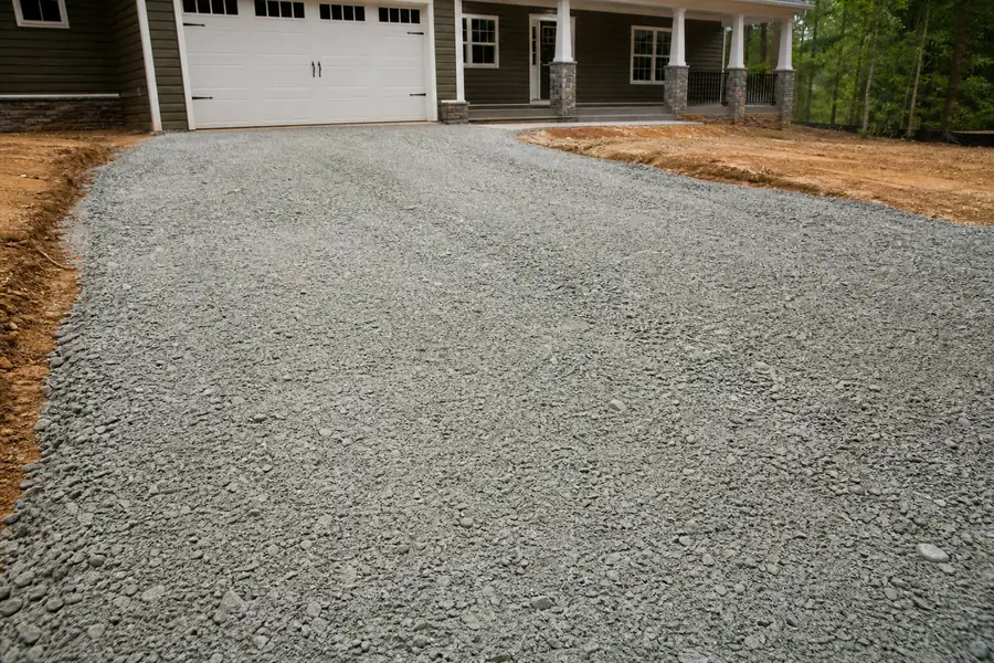 Compacted gray crush and run driveway base freshly graded before a North Carolina home