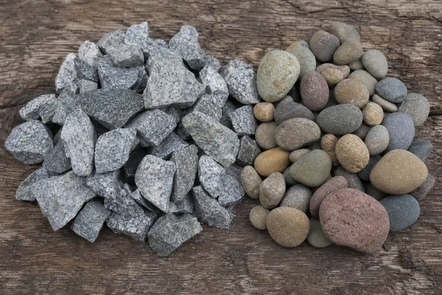 Angular crushed granite beside rounded river gravel on a wooden board