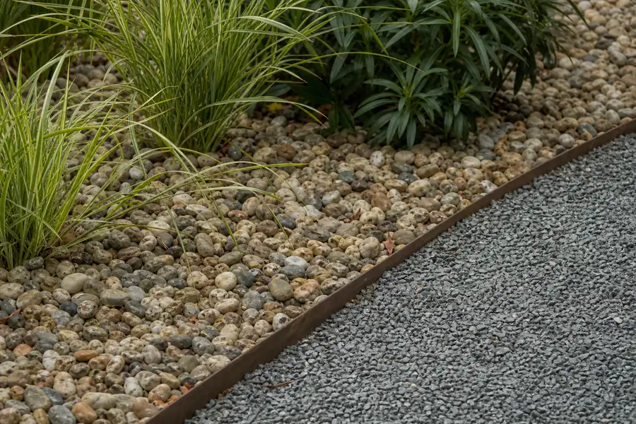 Rounded pea gravel in a garden bed next to a crushed stone path