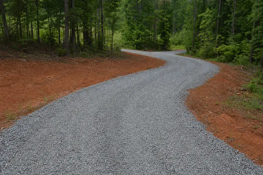 Freshly graded gravel driveway curving through red clay soil in the Piedmont