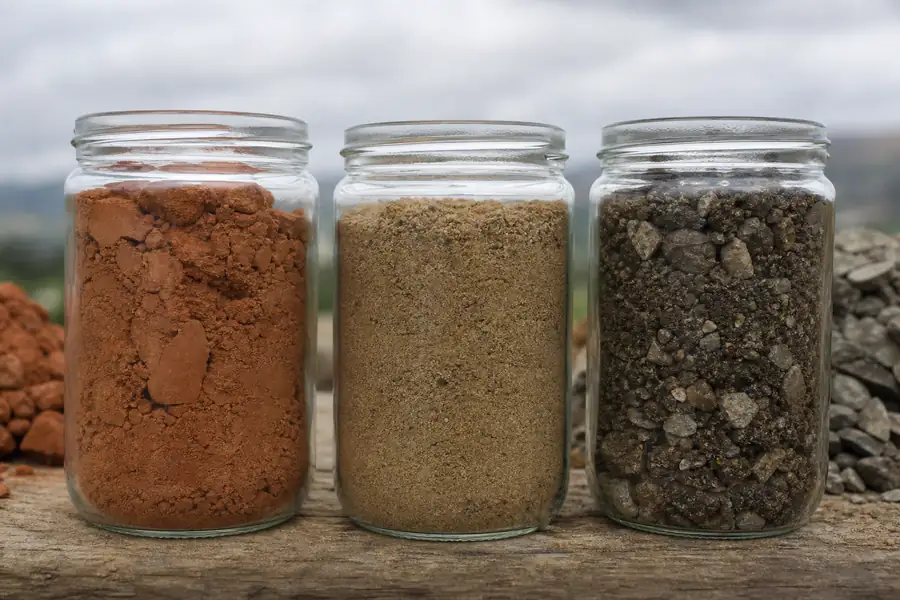 Three soil samples in jars: red clay, sandy loam and rocky mountain soil