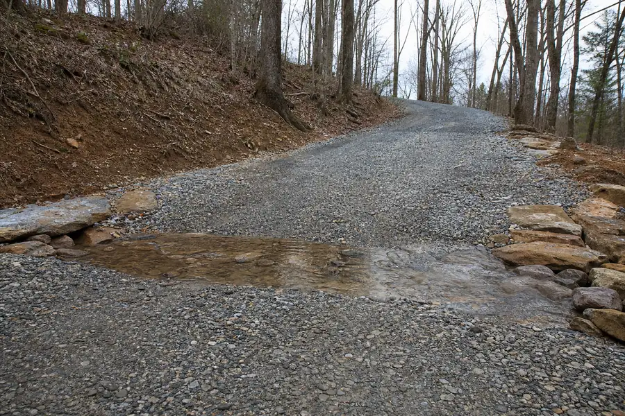 Rock-lined water bar cut across a sloped gravel driveway in the Blue Ridge foothills